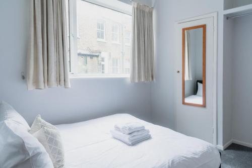 a bedroom with a bed with white sheets and a window at PER-64 64 Perham Road in London