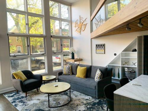 a living room with a couch and chairs and windows at Lincoln Park Light-Filled Loft in Chicago
