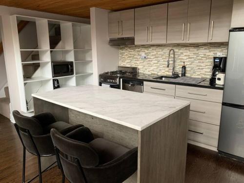a kitchen with a counter with chairs and a refrigerator at Lincoln Park Light-Filled Loft in Chicago