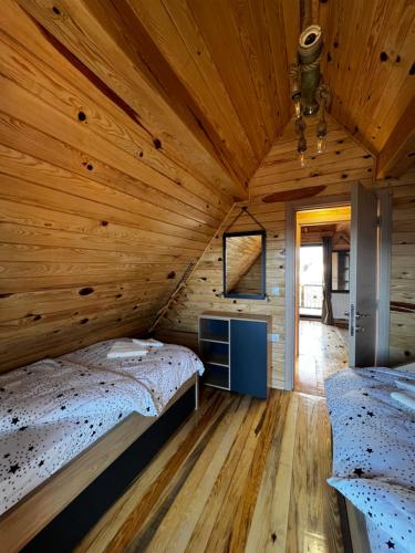 a room with two beds in a wooden cabin at Brvnara Pogled Zlatara in Nova Varoš