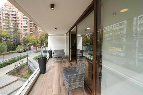 a building with a balcony with chairs and windows at AT HOME El Golf in Santiago