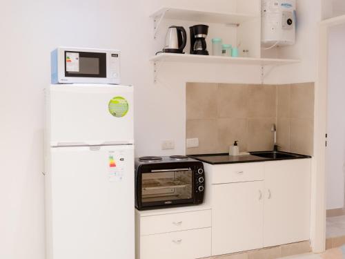 a white kitchen with a microwave and a refrigerator at BORGES HOUSE APARTS Aparts con cochera a dos cuadras del obelisco in Buenos Aires