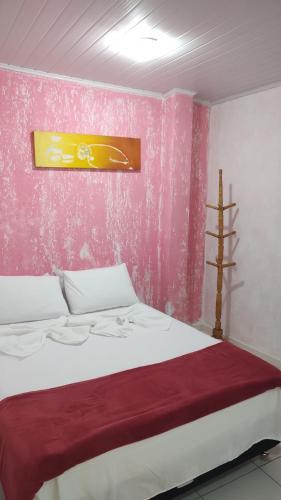 um quarto com uma cama com uma parede rosa em Casa tia Rosa hospedagem familiar em Guapimirim