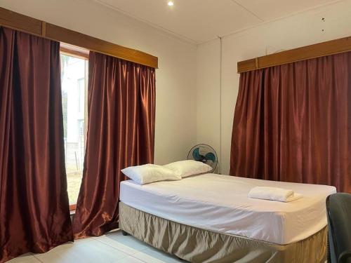 a bedroom with a bed with red curtains and a window at De la posh Travels and tours in Windhoek