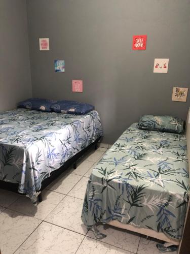 duas camas num quarto com cartazes na parede em Kitnet do Costa Praia do Pereque Guaruja!!! no Guarujá