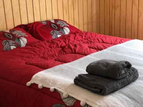 Una cama roja con un montón de toallas. en Cabañas Refugio Huillinco, en Huillinco