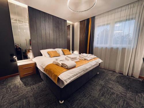 a bedroom with a large bed with towels on it at MOZAIK APARTMENTS & SPA - Modern 4-Star Apartments with Exclusive Private SPA WELLNESS in the City Center - SAUNA, JACUZZI, TURKISH BATH - FREE PARKING, Wi-FI - Rooms & Apartments Cuprija in Ćuprija