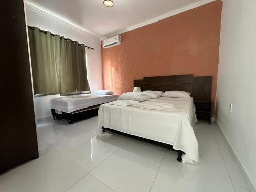a hotel room with two beds and a window at Apartamento da Jana a 1,5km praia in Porto Seguro