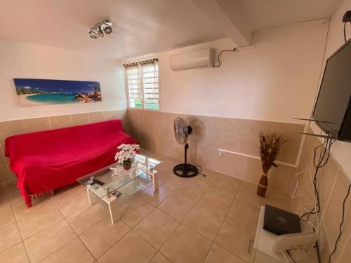 een woonkamer met een rood bed en een tafel bij La maison du plateau in Vieux-Habitants