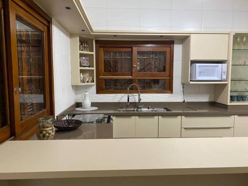 eine Küche mit einer Spüle und einer Mikrowelle in der Unterkunft Casa 100 metros da praia - 3 quartos in Imbituba