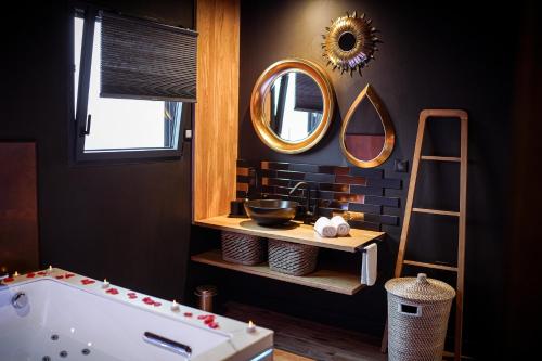 ein Bad mit einer Badewanne und Spiegeln an der Wand in der Unterkunft * L’Eden * Maison romantique avec balnéo et sauna in Treize-Vents