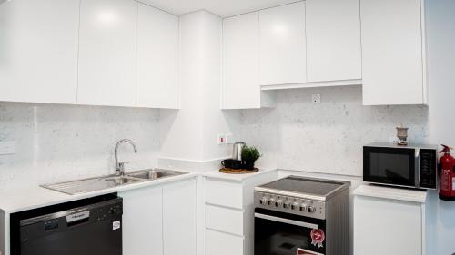 a white kitchen with a sink and a microwave at Spectacular 2BR Apartment Full BurjAlArab View in Dubai