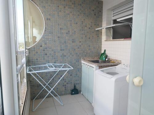 een kleine badkamer met een wasmachine en een spiegel bij Excelente Cobertura Duplex in Cabo Frio
