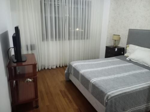 a bedroom with a bed and a flat screen tv at MC departamento in Río Cuarto