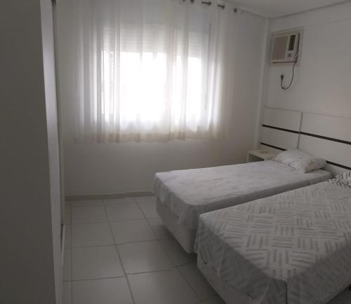 een witte kamer met 2 bedden en een raam bij Pe na areia in Florianópolis
