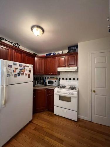 a kitchen with white appliances and wooden cabinets at Lovely Full Apartment x East Village (Thompkins Square Park) in New York