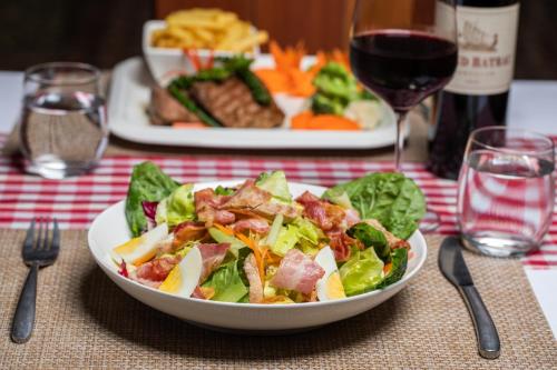 a table with a plate of salad and a glass of wine at Cambana Poipet Hotel in Krong Poi Pet