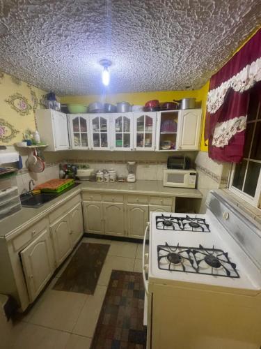 a kitchen with white cabinets and a stove top oven at Jamaican J Home in Kingston