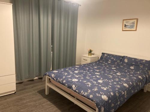 a bedroom with a bed with a blue floral bedspread at Kingdom Holiday - 12 Hamilton in London