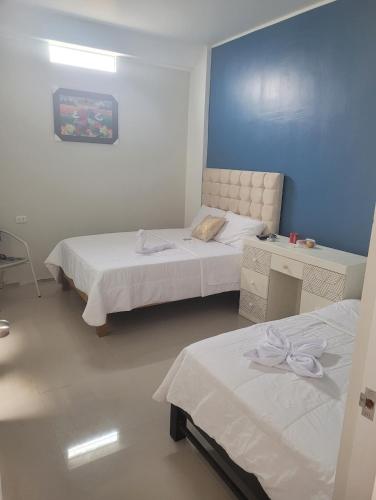 1 dormitorio con 2 camas y pared azul en CASA MARIA, en Pisco
