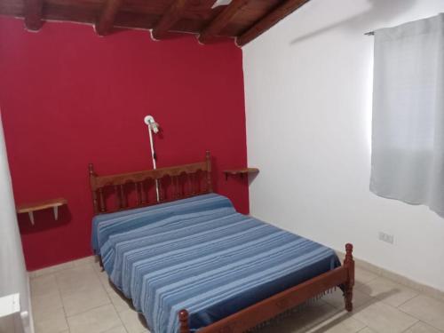 een bed in een kamer met een rode muur bij Mi Recreo in Villa Cura Brochero