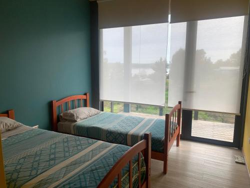 1 dormitorio con 2 camas y ventana grande en Casa Familiar Lago Rapel, en Las Balsas
