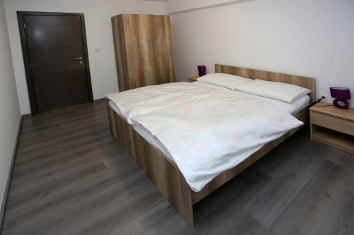 a bedroom with a large bed with a wooden headboard at Apartment Travego II in Osijek