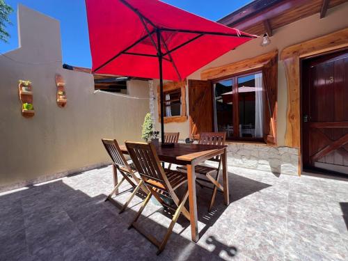 a wooden table and chairs with a red umbrella at CABAÑAS MECHI in Mar del Plata