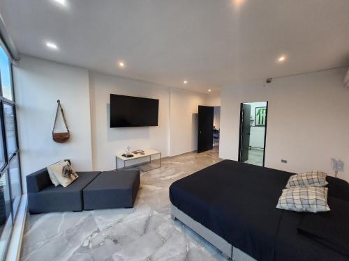 a bedroom with a bed and a couch and a tv at Amazonia Deluxe Calle 13 in Leticia