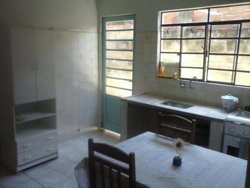 uma cozinha com uma mesa e um lavatório e duas janelas em Hostel Sancris 2 em São José dos Campos
