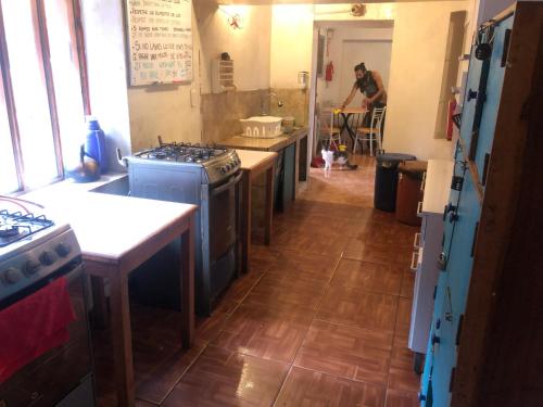 皮薩克的住宿－Intihuatana Hostel，一间厨房,厨房内配备了家电,后面是一位男士