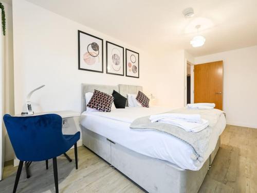 a bedroom with a bed and a blue chair at Stylish & Spacious Salford Quays one bedroom high floor apartment with balcony in Manchester