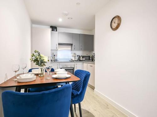 a kitchen with a wooden table and blue chairs at Stylish & Spacious Salford Quays one bedroom high floor apartment with balcony in Manchester