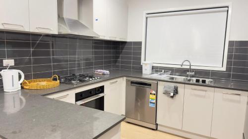 a kitchen with white cabinets and stainless steel appliances at Home in Wyndham Vale (Manor Lakes) Melbourne in Wyndham Vale