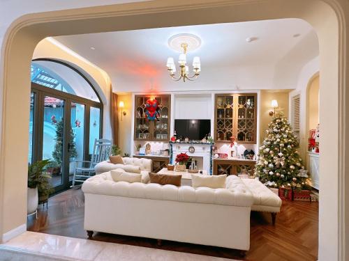 a living room with a white couch and a christmas tree at Moon Homestay in Thôn Kim Long (1)