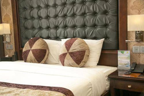 a bed with a black leather headboard and two pillows at CityBay Palace Hạ Long Hotel in Ha Long