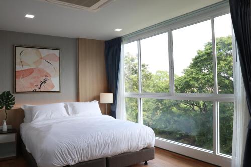 a bedroom with a bed and a large window at โรงแรมบลอสซั่ม เพชรบูรณ์ Blossom Hotel in Phetchabun