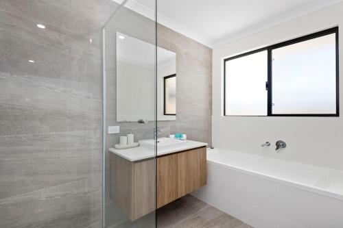 a bathroom with a tub and a sink and a mirror at Luxury Urban Retreat in Perth