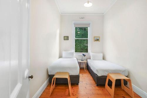 two beds in a room with two chairs and a window at Palm Cottage in Port Fairy
