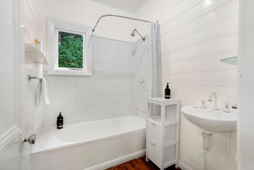 a white bathroom with a tub and a sink at Palm Cottage in Port Fairy