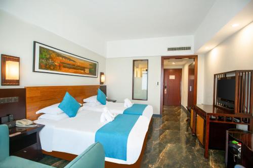 a hotel room with a bed and a flat screen tv at Shengyi Holiday Villa Hotel in Sanya