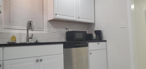 a kitchen with white cabinets and a black microwave at Cozy newly renovated house in Petersburg