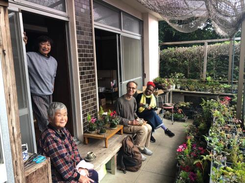 a group of people sitting on a porch with potted plants at Family Ryokan Kawakyu with Showa Retro, private hot spring in Ibusuki