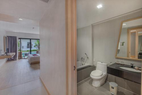 a white bathroom with a toilet and a sink at D Varee Mai Khao Beach Resort, Thailand in Mai Khao Beach