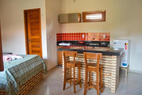 une cuisine avec un comptoir et deux tabourets de bar dans l'établissement Ap Classic - Pousada Flor da Serra - Mulungu, à Mulungu