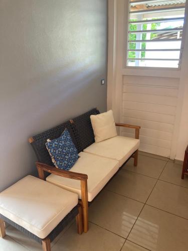 a couch and stool in a room with a window at Gîtes Hotel Couleur Caraibes in Bouillante