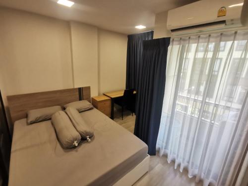 a bedroom with a bed with pillows and a window at Cozy room, BKK for short and long term rentals, 10mins walk to BTS, 25mins taxi to DMK airport in Ban Ko