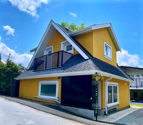 a yellow house with a balcony on a street at Vancouver’s Homey Laneway House in Vancouver