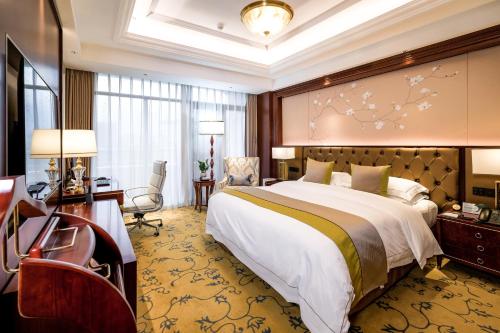 een hotelkamer met een groot bed en een bureau bij 潍坊富华大酒店a座 in Weifang