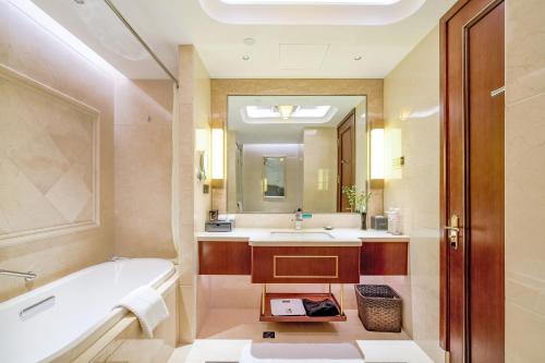 ein Badezimmer mit einer Badewanne, einem Waschbecken und einem Spiegel in der Unterkunft 潍坊富华大酒店a座 in Weifang